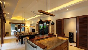 A modern kitchen with a large island, pendant lighting, and a ceiling fan.