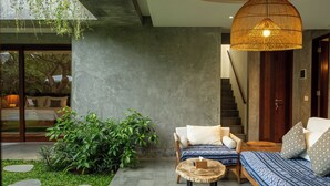 A modern interior with a sofa, a round wooden table, and a hanging light fixture.