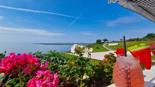 Ein Balkon mit Blick auf einen Golfplatz und ein Gewässer.