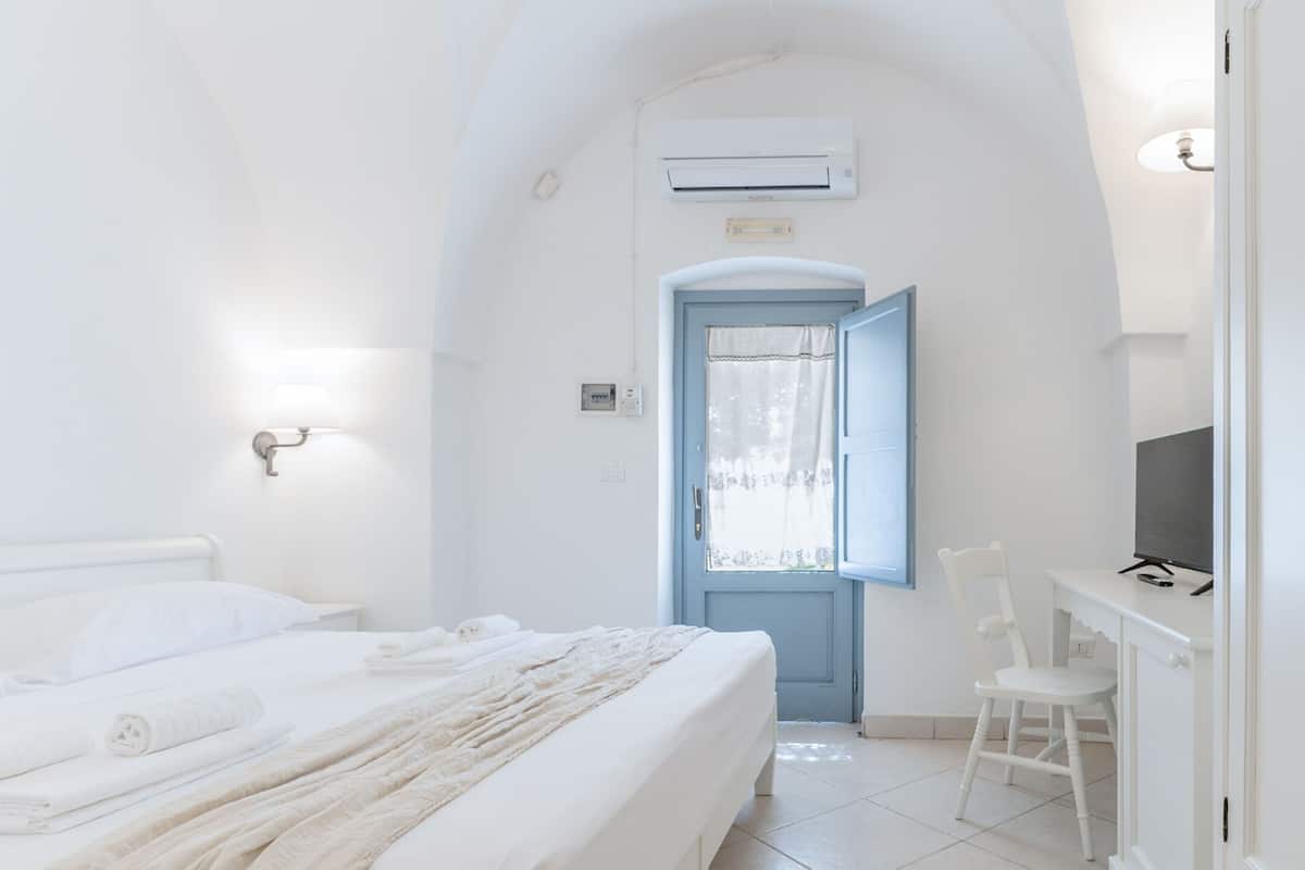 Ein helles Zimmer mit einem Bett, einem Schreibtisch und einem Stuhl.