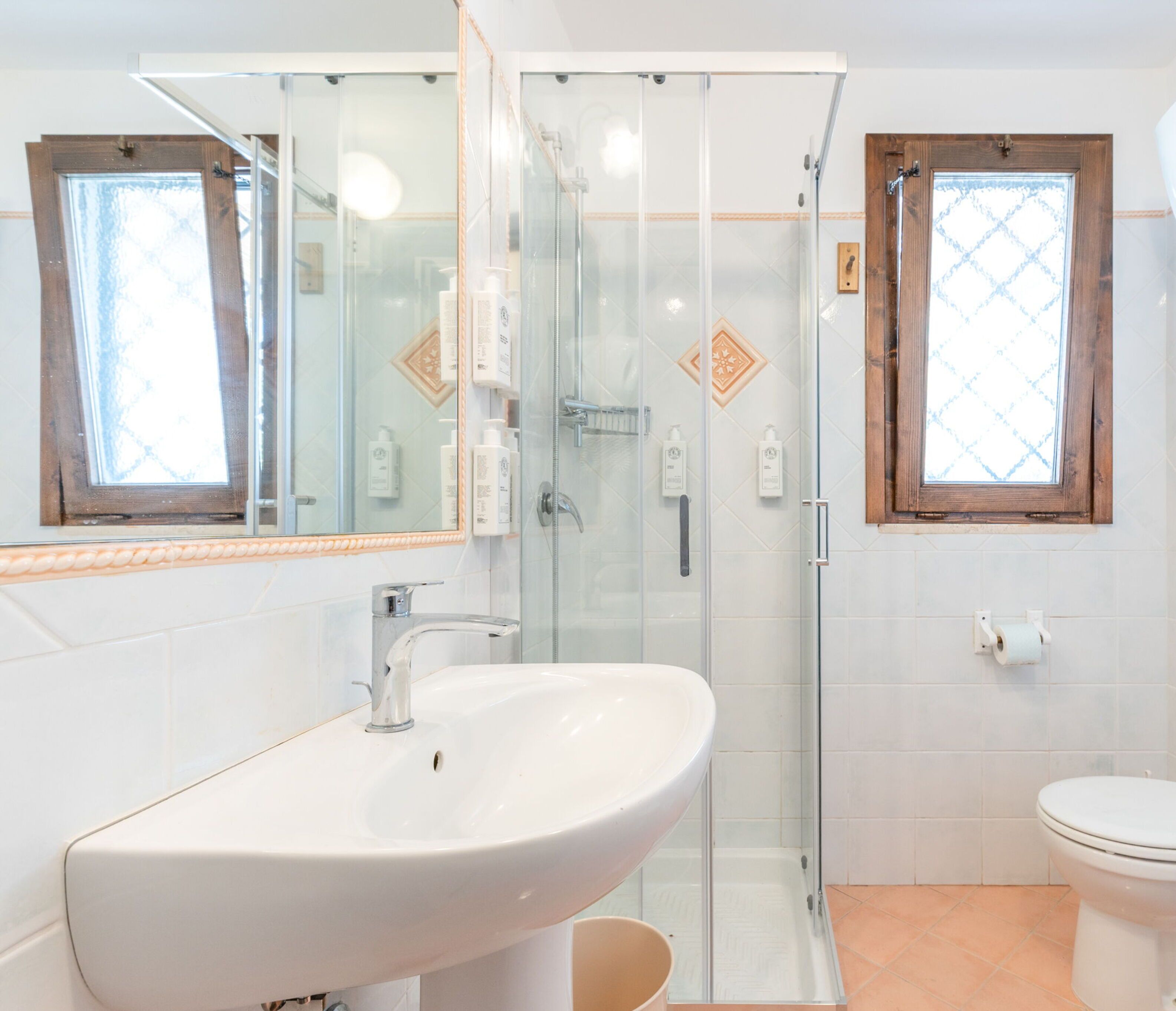 A bathroom with a glass-enclosed shower, a white sink, and a toilet.