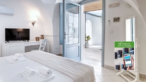 A hotel room with a bed, a desk, a television, and a self-check-in station. - Masseria Lamagrotte By Raro Rooms (Ostuni)