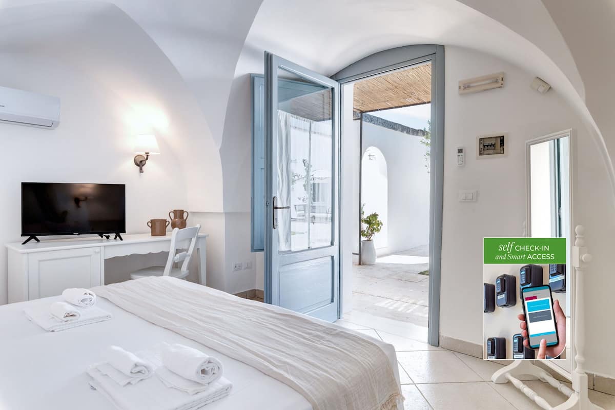Ein Hotelzimmer mit Bett, Schreibtisch, Fernseher und einer Selbstregistrierungsstation.