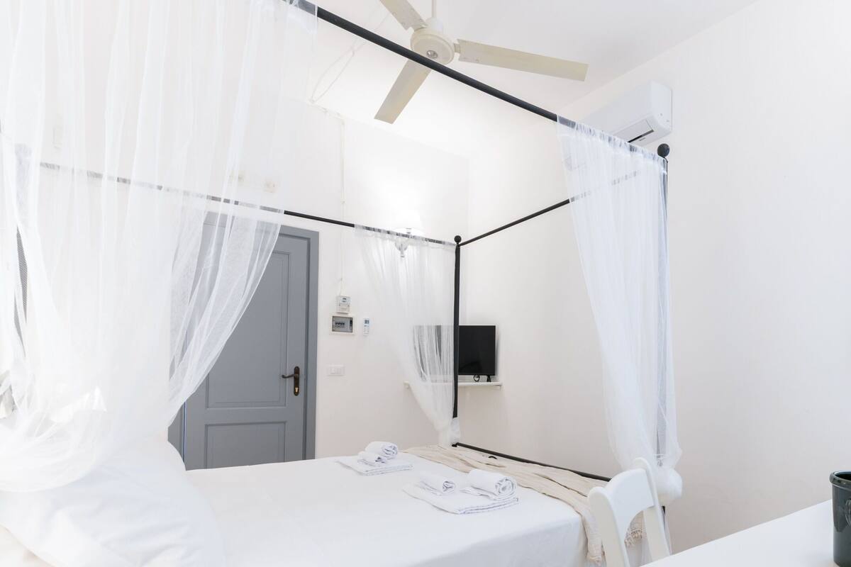 Ein Schlafzimmer mit einem Bett, einem Schreibtisch und einem Deckenventilator.