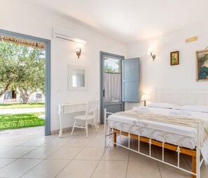 A bedroom with a bed, a desk, and a chair. There is a window with a view of greenery outside. - Masseria Lamagrotte By Raro Rooms (Ostuni)