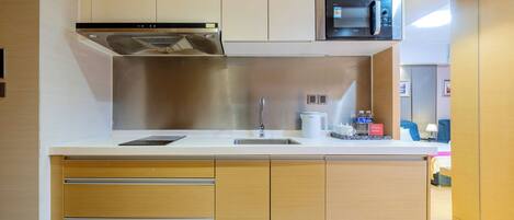 Una cocina moderna con un lavamanos de acero inoxidable, un microondas y armarios de madera.