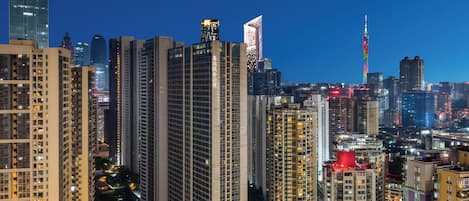 Un paisaje urbano con rascacielos, incluyendo una torre destacada con una exhibición de luces de arcoíris.