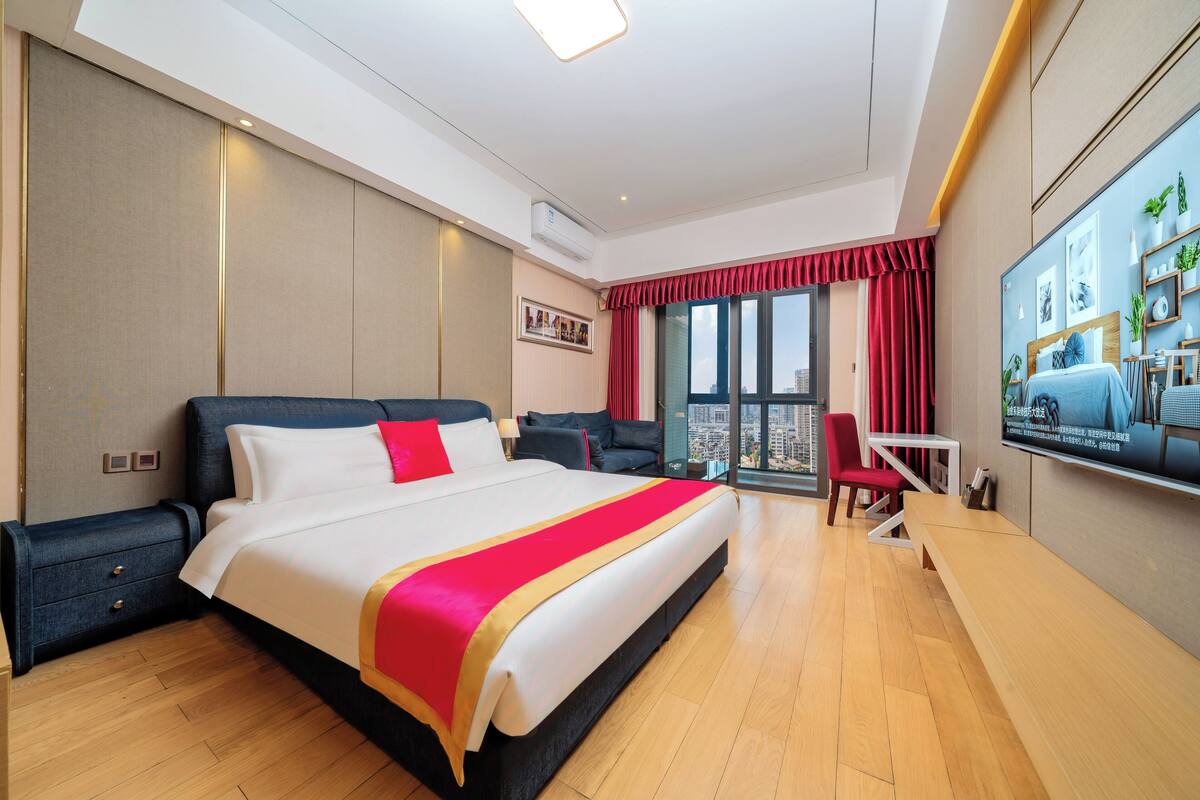 A modern hotel room with a large bed, a desk, and a TV.