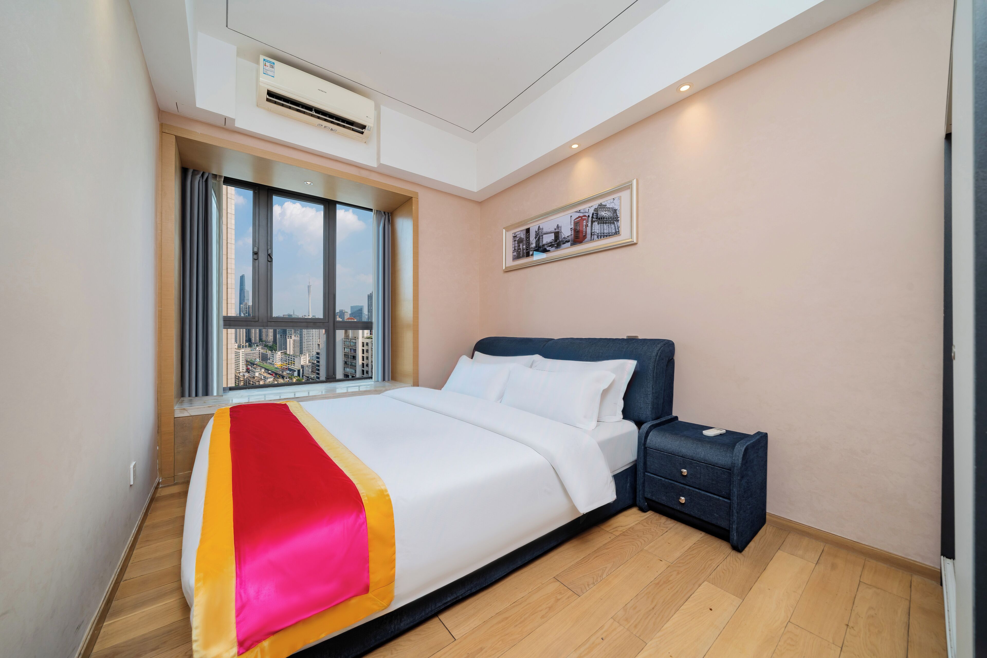 Quarto de hotel moderno com uma cama grande, uma mesa de cabeceira e uma janela com vista para a cidade.