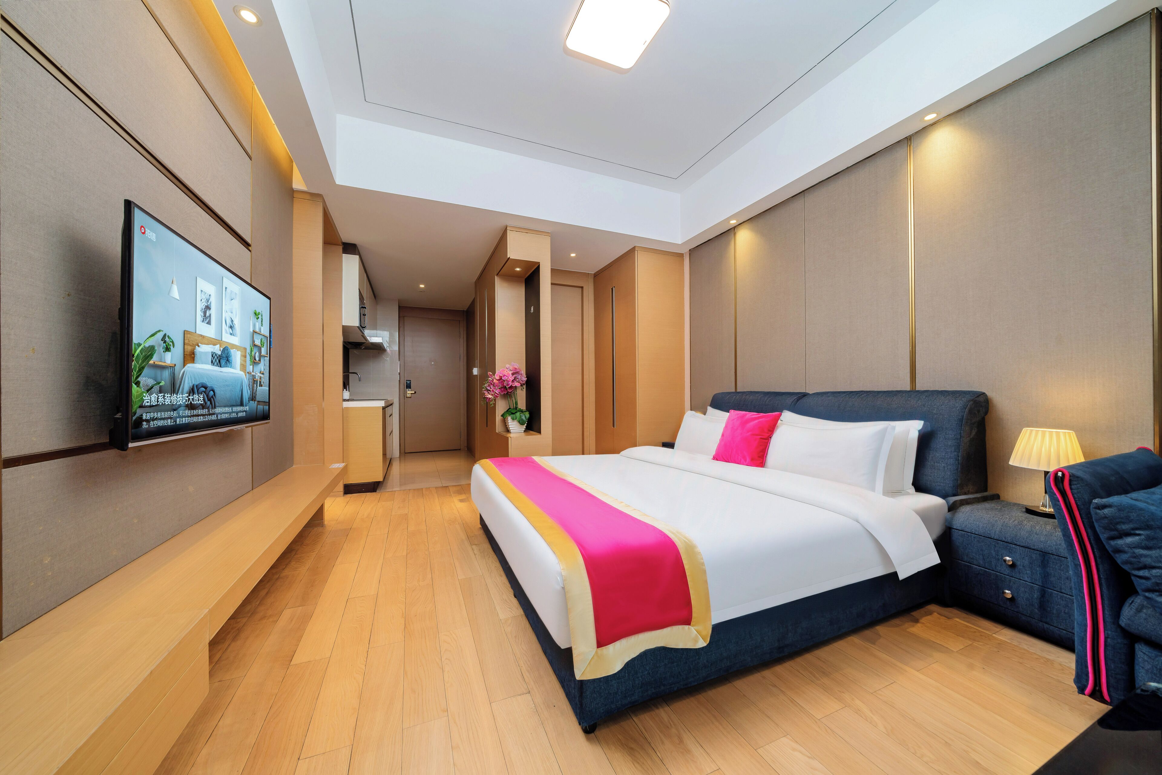 Una camera d'albergo moderna con un letto grande, comodini, una TV e un pavimento in legno.