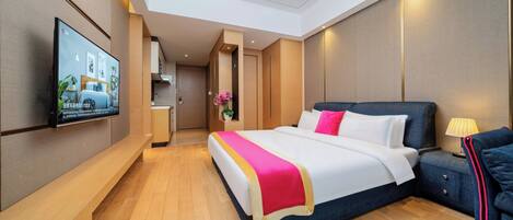 A modern hotel room with a large bed, bedside tables, a TV, and a wooden floor.