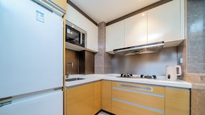 A modern kitchen with white cabinets, a stainless steel microwave, a gas stove, and a coffee maker. - Heefun International Apartment - Free Shuttle to Canton Fair (Guangzhou)