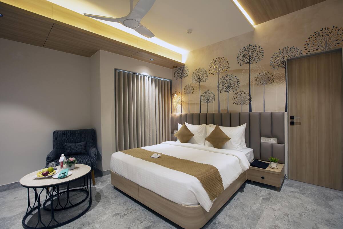 A modern hotel room with a large bed, a round table, a chair, and a ceiling fan.