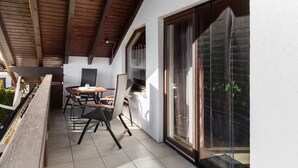 A covered patio with a table and chairs, a TV, and a sliding glass door.