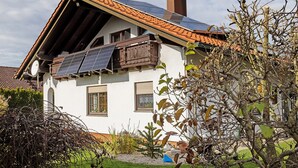 A house with a sloped roof, solar panels, and a chimney.