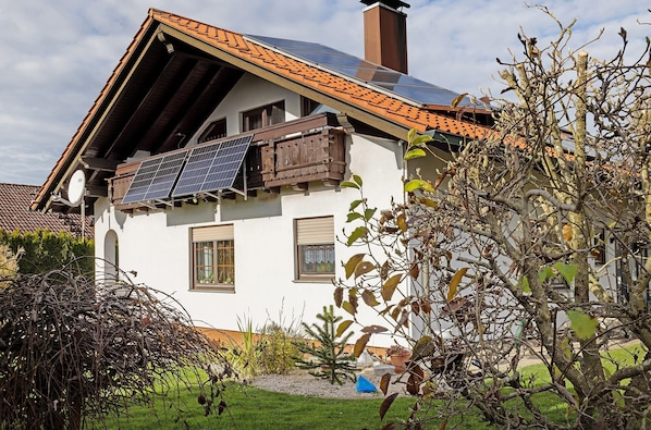 A house with a sloped roof, solar panels, and a chimney.