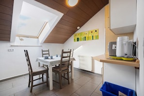 A dining area with a table, chairs, a ceiling fan, a radiator, and a coffee machine.