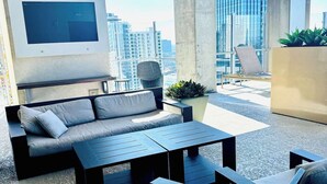 Un espace extérieur moderne aménagé avec un canapé, deux tables et des chaises, offrant une vue sur le paysage urbain.