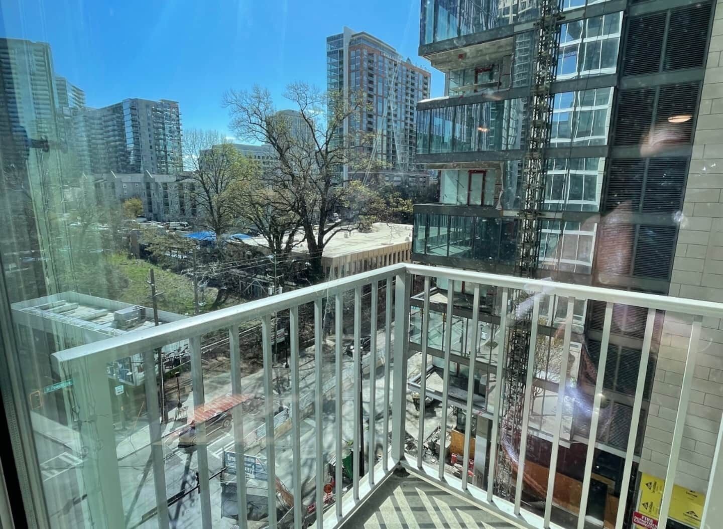 Un immeuble de grande hauteur doté d’une façade en verre, de nombreux étages et offrant une vue sur le paysage urbain, avec d’autres bâtiments et un parc.