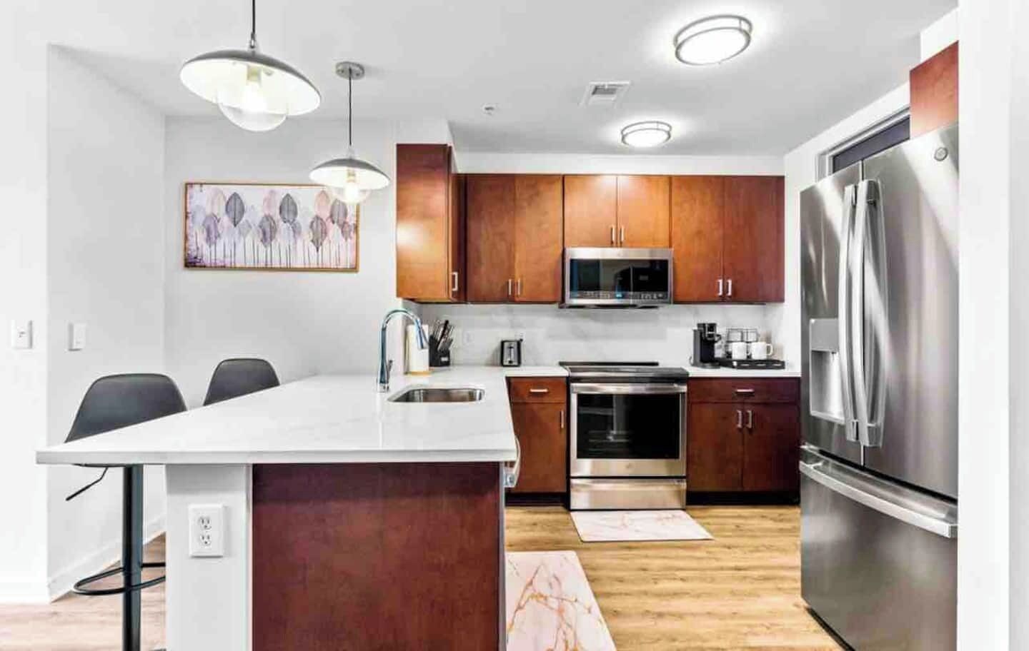 A modern kitchen with wooden cabinets, stainless steel appliances, and pendant lighting.