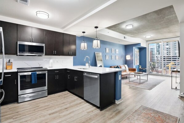 A modern kitchen with dark cabinetry, stainless steel appliances, and a central island.