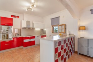 A modern kitchen with red and white cabinetry, a central island, and a view of the outdoors.