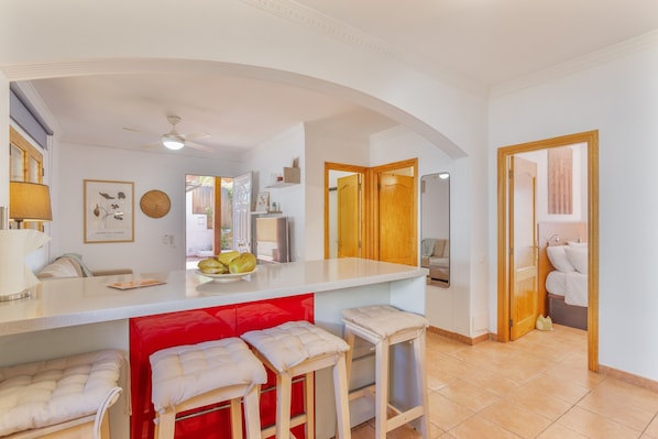A modern kitchen with a white countertop, red accents, and a ceiling fan.