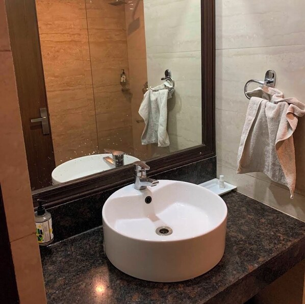 A bathroom with a round white sink, a mirror, and two towels hanging on towel bars. - HOTEL S C RESIDENCY (Dera Bassi)