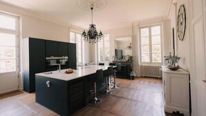Uma cozinha espaçosa com ilha central, armários escuros e um candelabro.