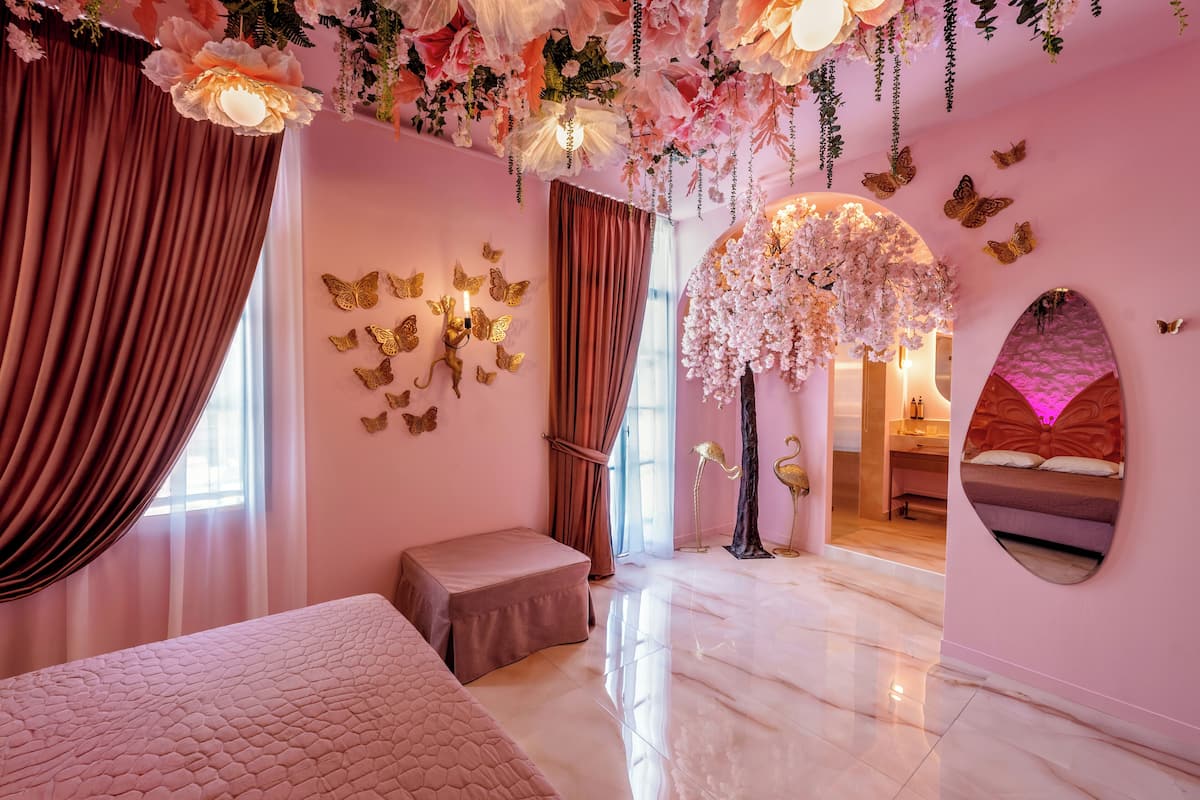 A pink-themed bedroom with a bed, a bench, and a decorative tree.