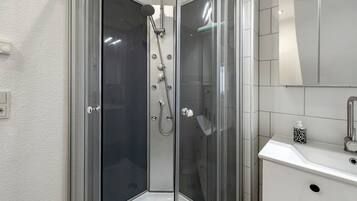 A modern bathroom with a glass-enclosed shower, a white sink, and a mirror.