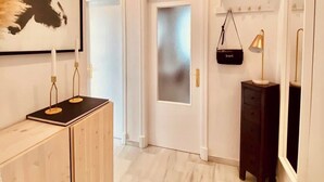 A hallway with a wooden cabinet, a framed artwork, a door with frosted glass, a small black shelf with a lamp, and a mirror. - Cozy Penthouse in the center. Air conditioning (Jerez de la frontera)