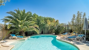 Piscina com espreguiçadeiras e palmeiras.