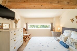 Un dormitorio con cama, cómoda, silla, mesita de noche, lámpara y ventana con vistas.