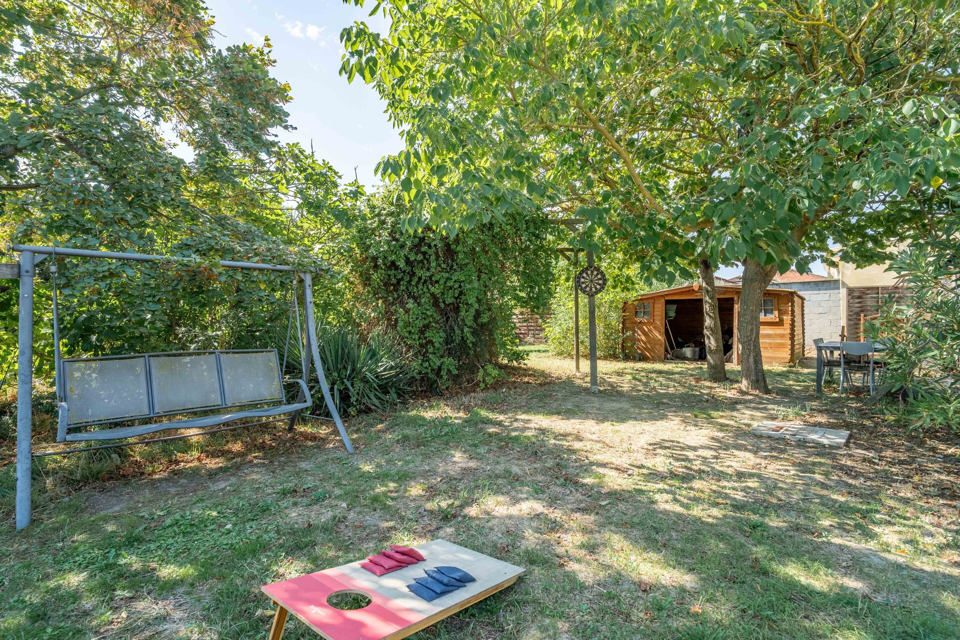 Een achtertuin met een schommel, een picknicktafel en een houten tuinhuis.