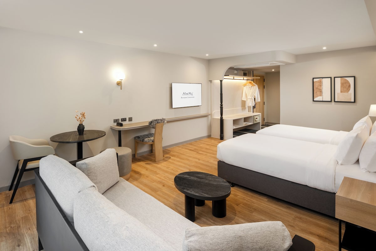 Una habitación de hotel moderna con sofá, una mesita redonda, una cama y un escritorio.