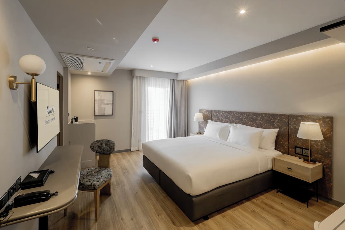 Una habitación de hotel moderna con una cama grande, mesitas de noche, un escritorio y una silla.