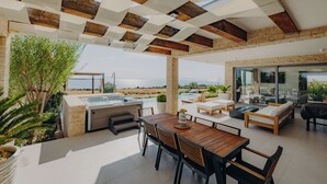 Une terrasse extérieure moderne, dotée d’une table et de chaises en bois, d’un jacuzzi et de coins salon confortables.