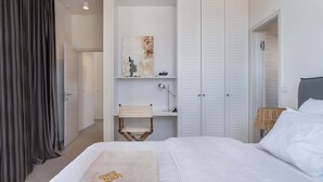 Une chambre à coucher avec un lit, un bureau et une chaise, une armoire et un tableau accroché au mur.