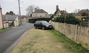 A residential street with houses, a car parked on the side, and a grassy area. - Continued from Solognote (Neuvy-sur-Barangeon)