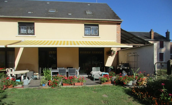 A two-story house with a covered patio area, outdoor furniture, and potted plants. - Continued from Solognote   (Neuvy-sur-Barangeon)