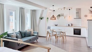 A modern apartment with a living room, dining area, and kitchen.