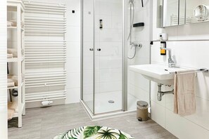 A modern bathroom with a glass shower enclosure, a white sink, and a towel rack. - 07 Deichstadt-Apartments Neuwied   116m² (Neuwied)