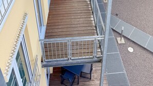 A multi-level outdoor deck with metal railings, wooden flooring, and seating areas.
