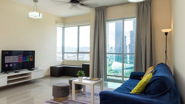 A modern living room with a flat-screen TV, a sofa, a coffee table, and a large window with a city view.