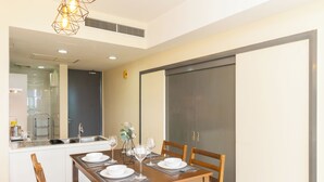 A dining area with a wooden table set for four, a kitchen in the background, and a sliding door closet.
