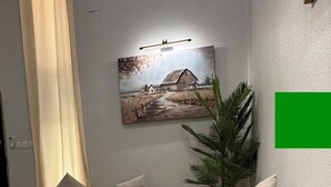 Un salon avec deux canapés beige, une table basse et un tableau représentant un paysage rural.