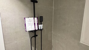 Une douche équipée d’un pommeau de douche à pluie noir, d’un pommeau de douche à main et d’un appareil de massage portatif.