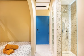 A hotel room with a bed, a blue door, and a shower area. - Studio Deluxe Blue - with balcony (Marrakech)