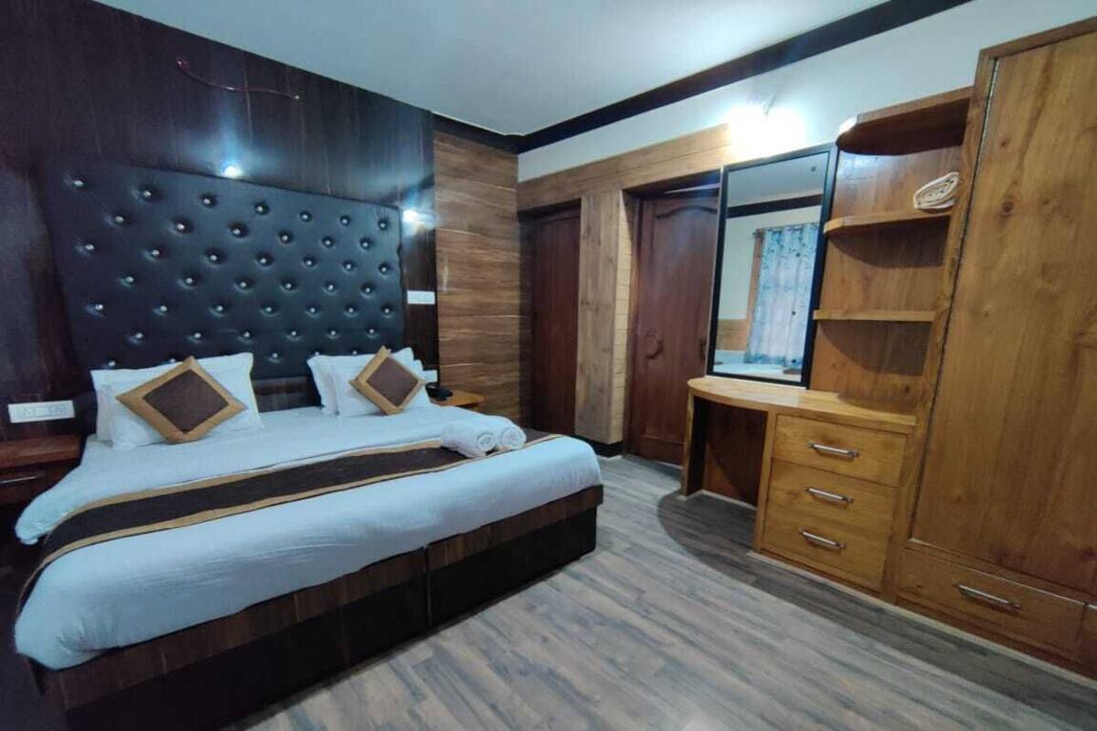 A bedroom with a large bed, wooden wardrobe, and a mirror.